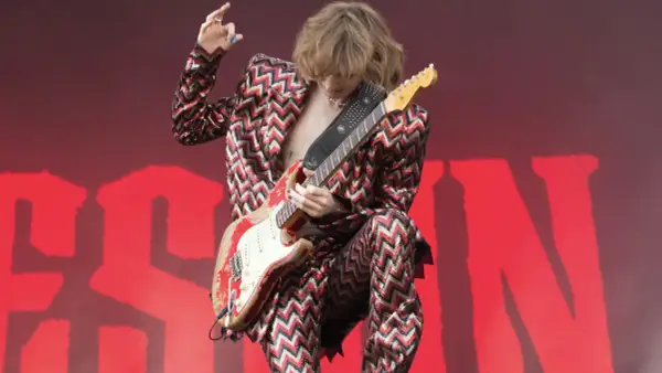 Thomas Raggi, chitarrista dei Måneskin, con la sua iconica chitarra rossa e un completo a zig-zag, infiamma il palco con la sua energia.