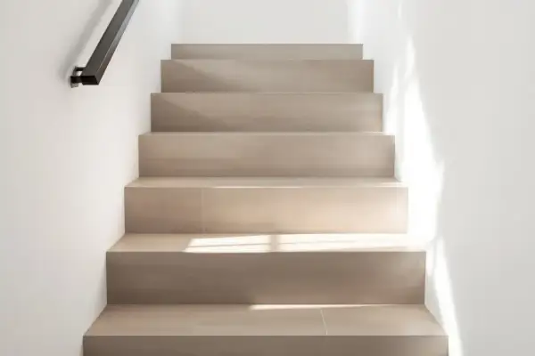 Escaliers en carrelage clair, sans joints apparents, avec un éclairage doux. On peut marcher sur du carrelage sans joint pour un look épuré.