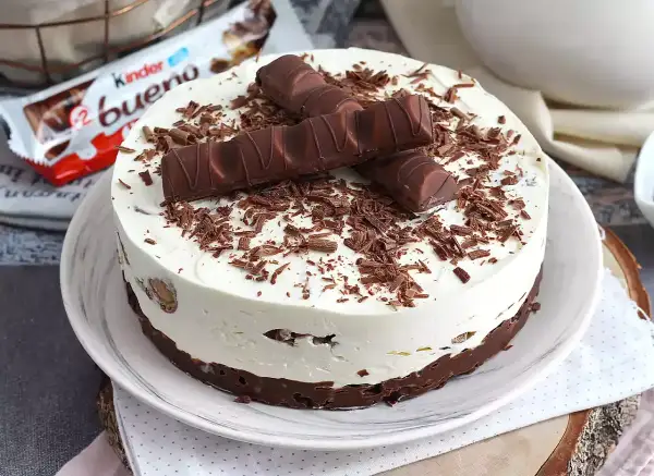 Pyszna tarta Kinder Bueno z kremem i czekoladowymi wiórkami, ozdobiona batonikami.