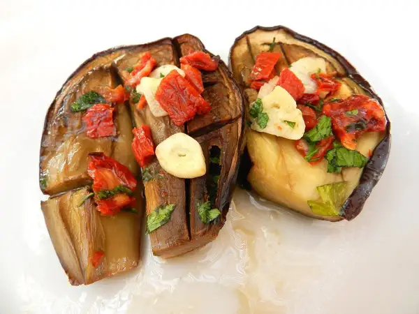 Melanzane alla sassarese, un piatto saporito con melanzane cotte, pomodori secchi, aglio e prezzemolo.