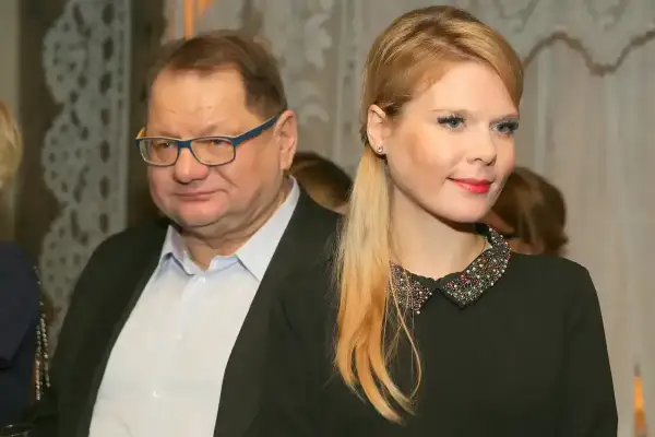 Mężczyzna w okularach i jego żona, ubrana w czarną sukienkę z ozdobnym kołnierzykiem, pozują do zdjęcia.