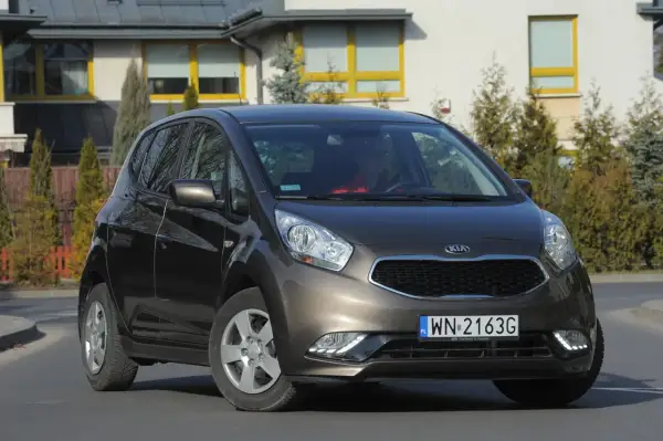 Brązowa Kia Venga z nowymi żarówkami LED, zaparkowana przed nowoczesnym domem.