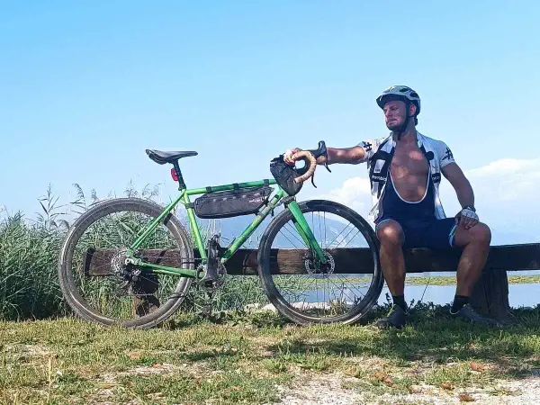 Ciclista riposa accanto alla sua bici verde, un promemoria che andare in bici fa dimagrire e dona benessere.