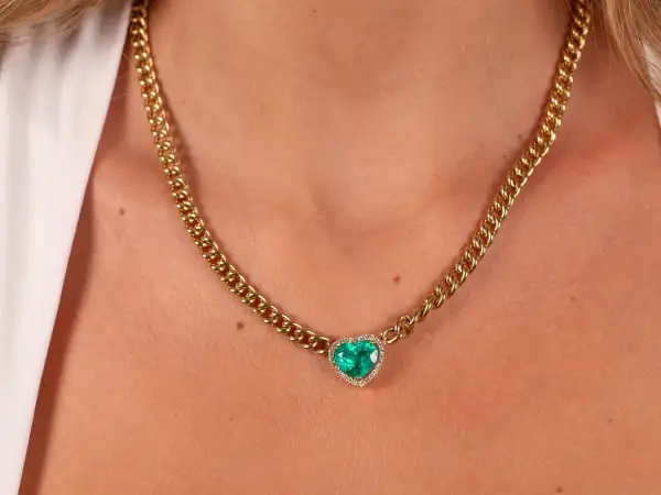 Collar de oro con colgante de corazón de esmeralda y diamantes. Un ejemplo de nombres de joyas que evocan elegancia y amor.