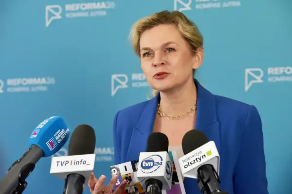 Kobieta w niebieskiej marynarce przemawia do mediów, omawiając zmiany w karcie nauczyciela.
