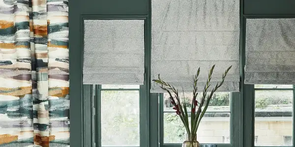 Tende a pacchetto grigie scintillanti fino al davanzale, accanto a una tenda con pennellate astratte colorate.