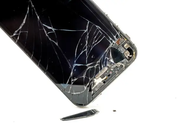 Rozbite szkło telefonu. Widać pęknięcia i fragmenty, które odpadły. To pokazuje, czym się różni szkło hartowane od hybrydowego w praktyce.