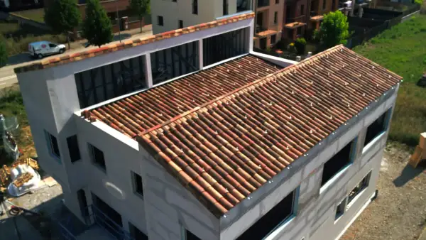 Edificio en construcción con tejado de tejas rojas, una cubierta plana o inclinada que protege la estructura.