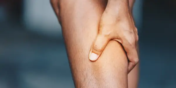 Hand greift an schmerzendes Bein. Was hilft gegen Muskelschmerzen?