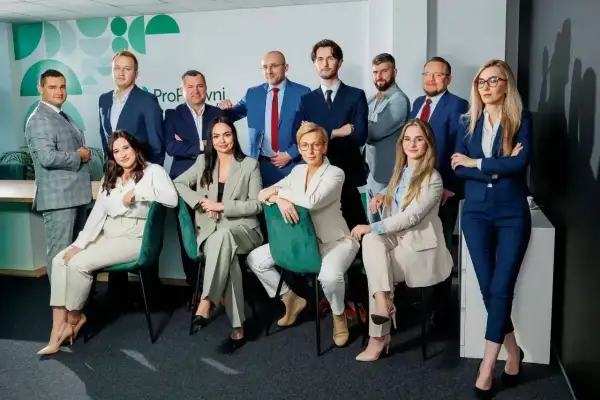 Grupa prawników w garniturach pozuje do zdjęcia w biurze.