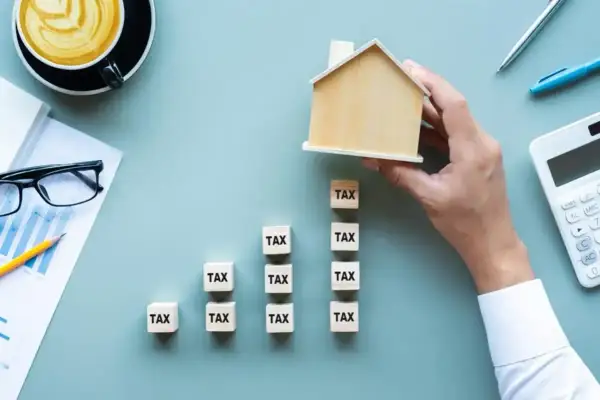 Klocki z napisem "TAX" tworzą rosnący wykres, a dłoń kładzie na szczycie domek. Zastanawiasz się, do kiedy trzeba zapłacić podatek?