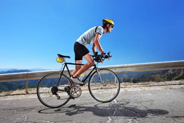 Kolarz w kasku i okularach pokonuje górską trasę. Czy 100 km na rowerze to dużo? Dla niego to wyzwanie!