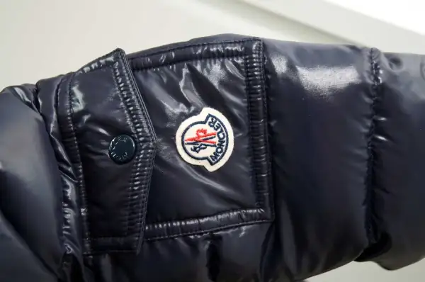 Granatowa, błyszcząca kurtka z naszywką Moncler. Czy to właśnie ta firma, o którą pytasz?