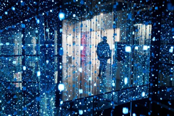 Osoba wchodzi do instalacji świetlnej, jednego z nietypowych miejsc w Warszawie. Błękitne światła tworzą iluzję nieskończoności.