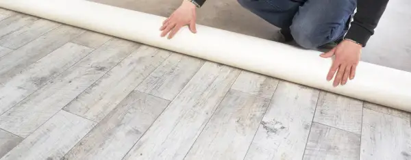Eine Rolle Unterlage liegt auf einem Holzboden. Sie ist ideal, wenn Sie sich fragen, was kommt unter PVC Boden.