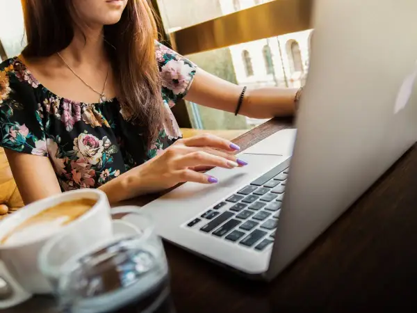Ragazza con laptop e caffè, mentre cerca la differenza ferie e permessi.