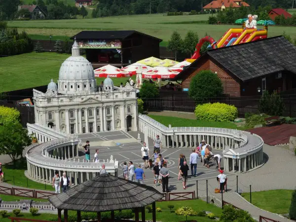 Miniaturowy park z modelem Bazyliki św. Piotra i placem Berniniego. W tle zjeżdżalnia i budynki. Sprawdź inwałd park cennik.