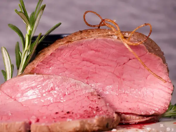 Saftiges Rinderfilet im Backofen, perfekt rosa gebraten, mit Rosmarin und einer dekorativen Schnur aus Bratensaft.
