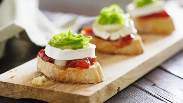 Deliciosos pinchos y tapas originales: rebanadas de pan con queso de cabra, mermelada de pimientos y cebolla morada.