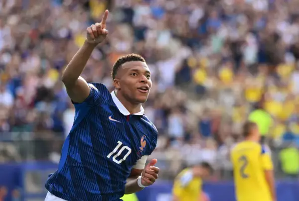 Kylian Mbappé, młody piłkarz, świętuje bramkę. Ile lat ma Mbappé? W tym momencie ma 25 lat.