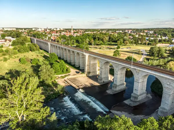 Kamienny wiadukt kolejowy nad rzeką, z miastem w tle. Bolesławiec atrakcje, które zachwycają.