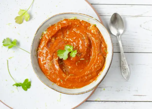Un tazón de cremosa salsa chipotle, adornado con cilantro fresco y ralladura de lima, listo para acompañar tus platillos.