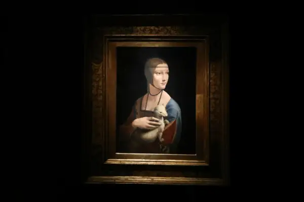 Obraz Dama z łasiczką, Leonarda da Vinci. Młoda kobieta w niebieskiej sukni trzyma w ramionach białego zwierzątko.