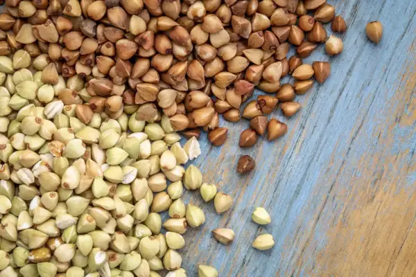Zielona i brązowa kasza gryczana na niebieskim tle. Czy kasza gryczana ma gluten? Nie, jest bezglutenowa!