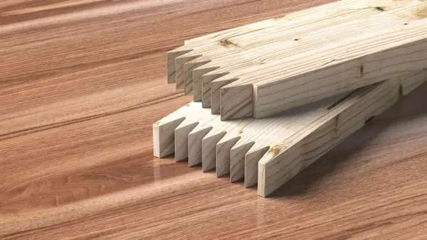 Dos tablas de madera con cortes en forma de dientes de sierra listas para unir tablero.