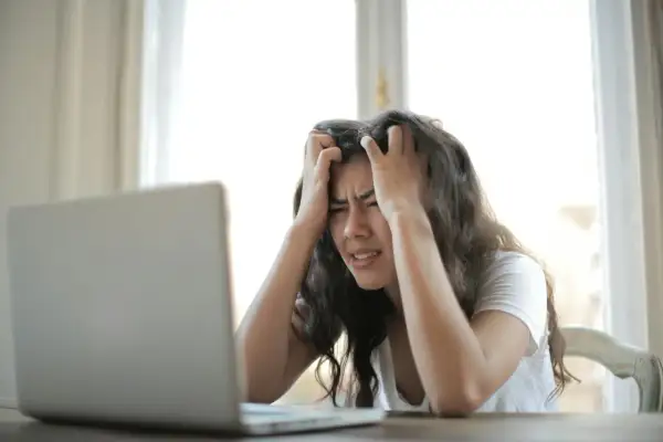 Kobieta z rękami we włosach, patrząca na laptopa z wyrazem frustracji. Czasem czuję, że moje życie to porażka.