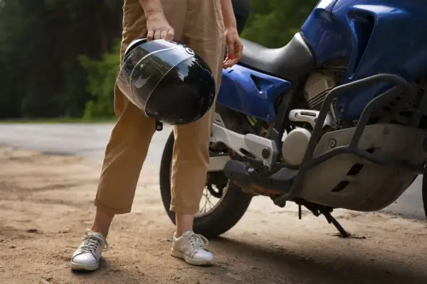 Osoba trzyma kask obok niebieskiego motocykla. Zastanawiasz się, czy można holować motocykl?