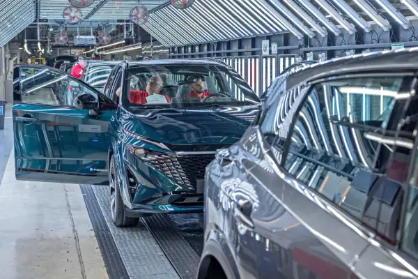 Nowy Nissan powstaje w fabryce. Pracownicy kontrolują jakość pojazdu, który opuszcza linię produkcyjną.