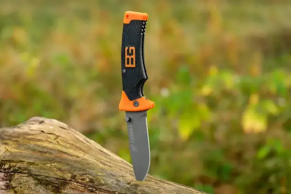 Cuchillo de supervivencia Gerber con mango naranja y negro, listo para la aventura en la naturaleza.