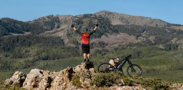 Ciclista celebra cima de montaña, listo para un camino de Santiago en bici con niños.