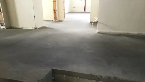 Surowy, betonowy jastrych co to? To podłoga gotowa na wykończenie. Widać fragmenty ścian i instalacji.