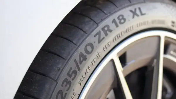 Gros plan sur un pneu de voiture avec l'inscription "235/40 ZR 18 XL", indiquant une capacité de charge renforcée pour une conduite sportive.