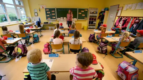 Ein helles Klassenzimmer, bereit für den Unterricht. Kinder sitzen an ihren Tischen, Rucksäcke und Lernmaterialien sind schon da. Das Klassenzimmer einrichten ist abgeschlossen.