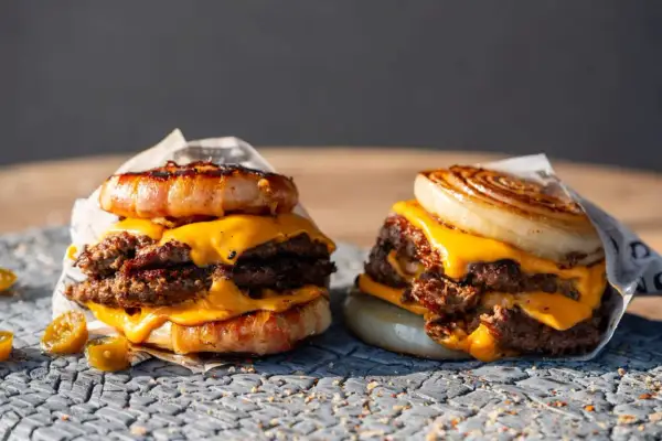 Zwei saftige "Flying Dutchman Burger" mit doppelt Fleisch, geschmolzenem Käse und einer Zwiebel- bzw. Speckkrone.