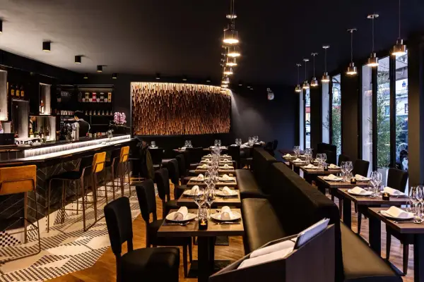 Ambiance chic d'un restaurant thaïlandais, avec un bar lumineux, des tables dressées et une décoration murale en bois.