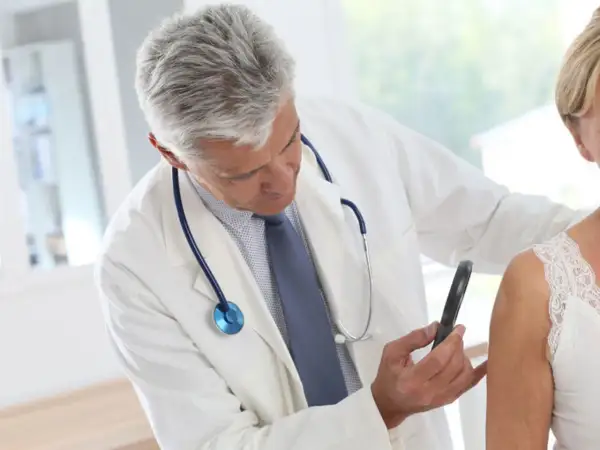 Dermatolog bada skórę pacjentki. Ważne, by wiedzieć, jak długo jest ważne skierowanie do dermatologa, aby nie przegapić terminu wizyty.