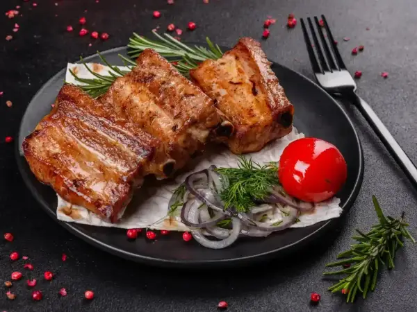 Soczyste żeberka w coli, podane z pomidorkiem, cebulą i rozmarynem. Idealne na obiad.