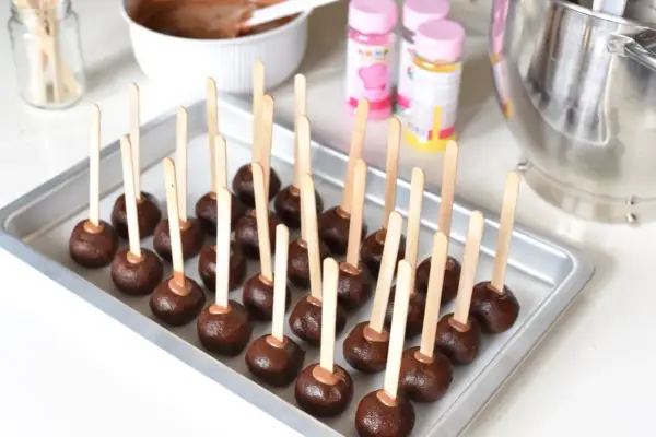 Chokladbollar på pinnar, redo att dekoreras. En bricka full med dessa goda cake pops väntar på att bli klädda i glasyr och strössel.