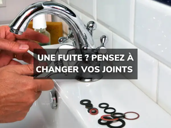 Main d'un bricoleur tenant une clé pour changer un joint de robinet. Des joints neufs sont disposés sur le lavabo.