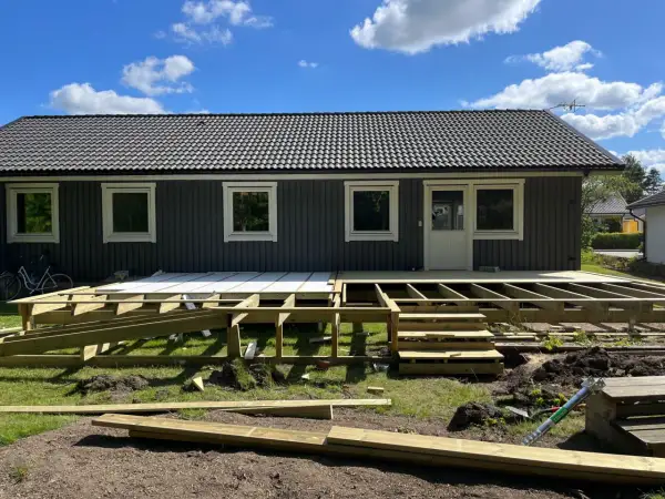 Grundarbete för att bygga veranda. Träkonstruktion och trappor på plats framför huset.