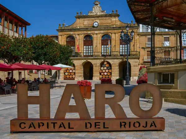 Letras gigantes "HARO CAPITAL DEL RIOJA" en plaza con Ayuntamiento y terraza. Descubre qué ver en Haro.