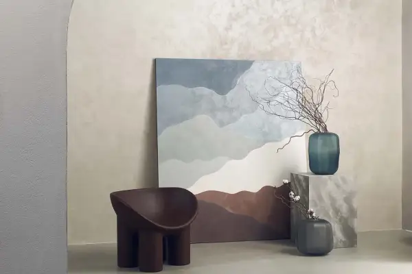 Parete con finitura materica, un quadro astratto e una poltrona dal design organico. La **decorative paint** crea un'atmosfera rilassante.