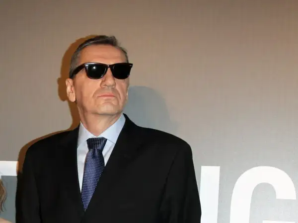 Władysław Pasikowski w czarnym garniturze i okularach przeciwsłonecznych, gotowy na premierę swojego kolejnego filmu.