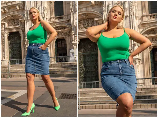 Kobieta w zielonym topie i jeansowej spódnicy plus size, pozuje na tle zabytkowej budowli.