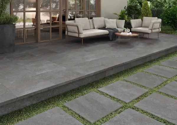 Terraza moderna con suelo de baldosas grises, ideal para pintar y renovar tu espacio exterior. Muebles de exterior y plantas verdes.