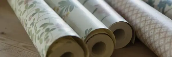 Rullar med tapet i olika mönster. Frågan om hur många våder på en tapetrulle är relevant för att beräkna materialåtgången.